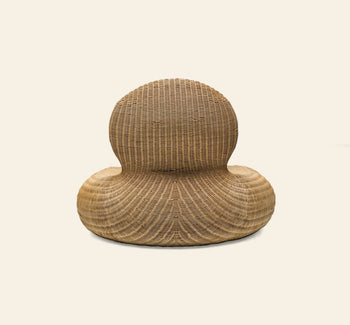 The IKEA Rattan Storvik Lounge Chair by IKEA features a sculptural, modern design with woven rattan, a round backrest, and a wide curved seat, inspired by vintage lounge chairs and set against an off-white background.
