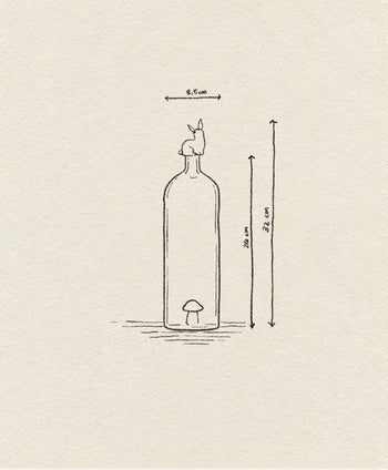 The Ichendorf Milano Alice Bottle by Ichendorf Milano features a simple line design of a tall, 20 cm bottle with a small colorful mushroom inside and a rabbit on top. Total height (with rabbit) is 23.2 cm, width is 9.5 cm—a unique charm for any space.