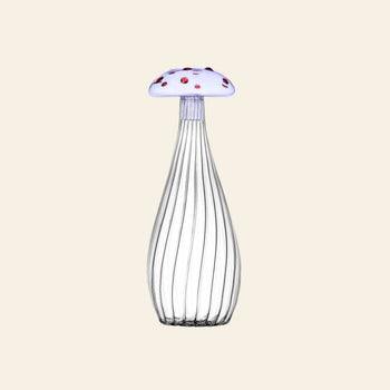 The Ichendorf Milano Alice Bottle by Ichendorf Milano features clear ribbed glass and a whimsical mushroom-shaped cap—white with red spots—set against a plain beige background.
