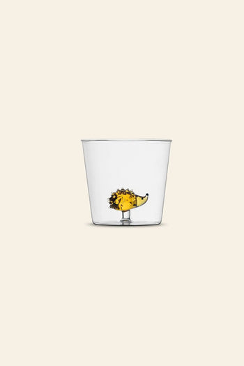 The Ichendorf Milano Animal Farm Tumbler by Ichendorf Milano is a clear glass featuring a handcrafted hedgehog-shaped base inside, holding yellow liquid, on a light beige background, making it look as if the liquid fills the hedgehog.
