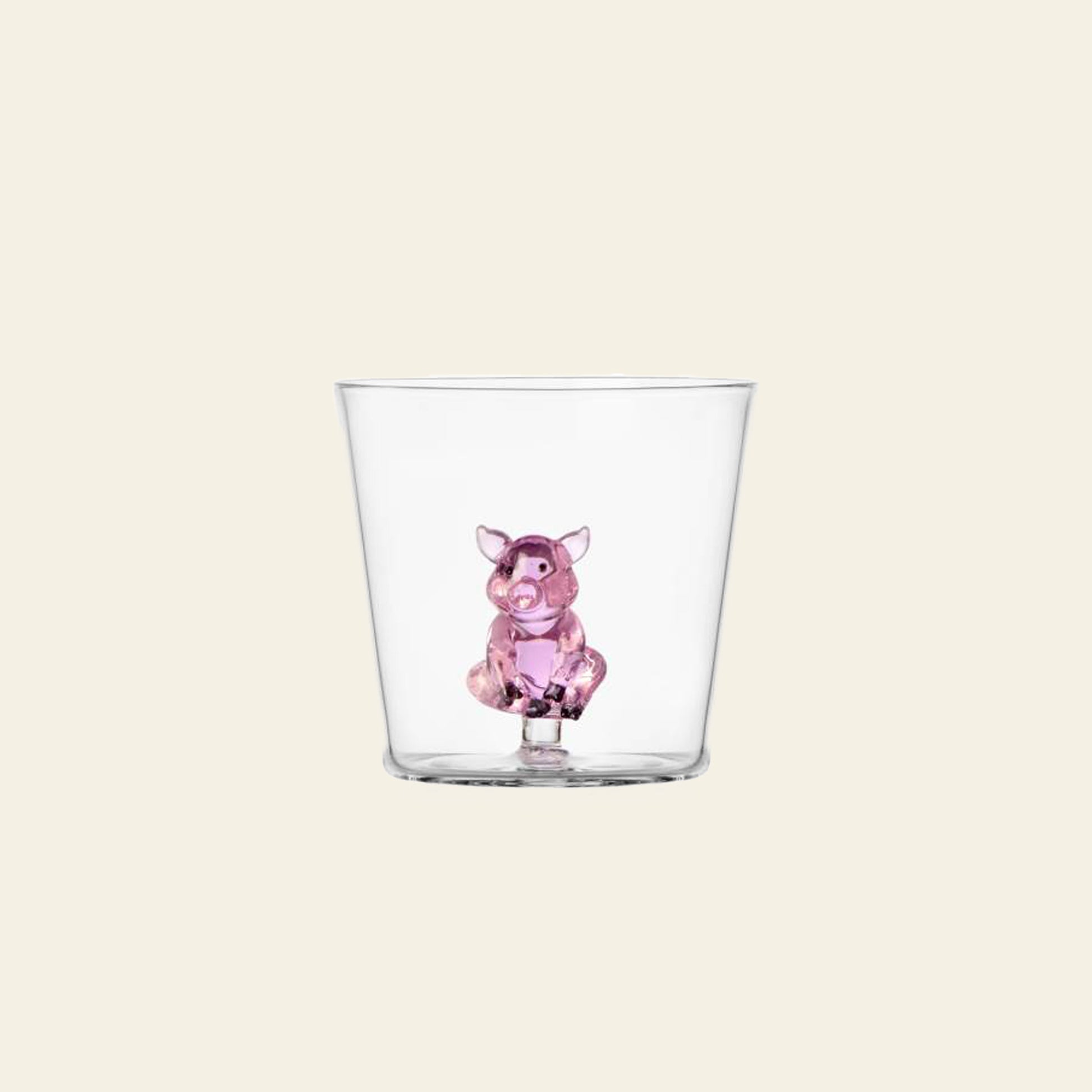The Ichendorf Milano Animal Farm Tumbler features a small pink pig figurine at the base, blending playful design with clear glass from Ichendorf Milano, shown against a simple light backdrop.