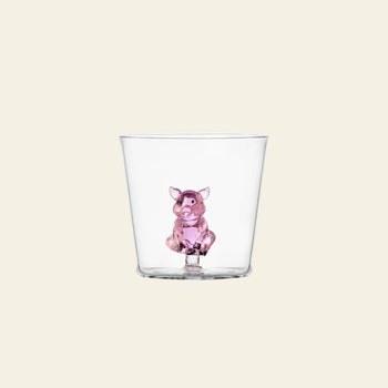 The Ichendorf Milano Animal Farm Tumbler features a small pink pig figurine at the base, blending playful design with clear glass from Ichendorf Milano, shown against a simple light backdrop.