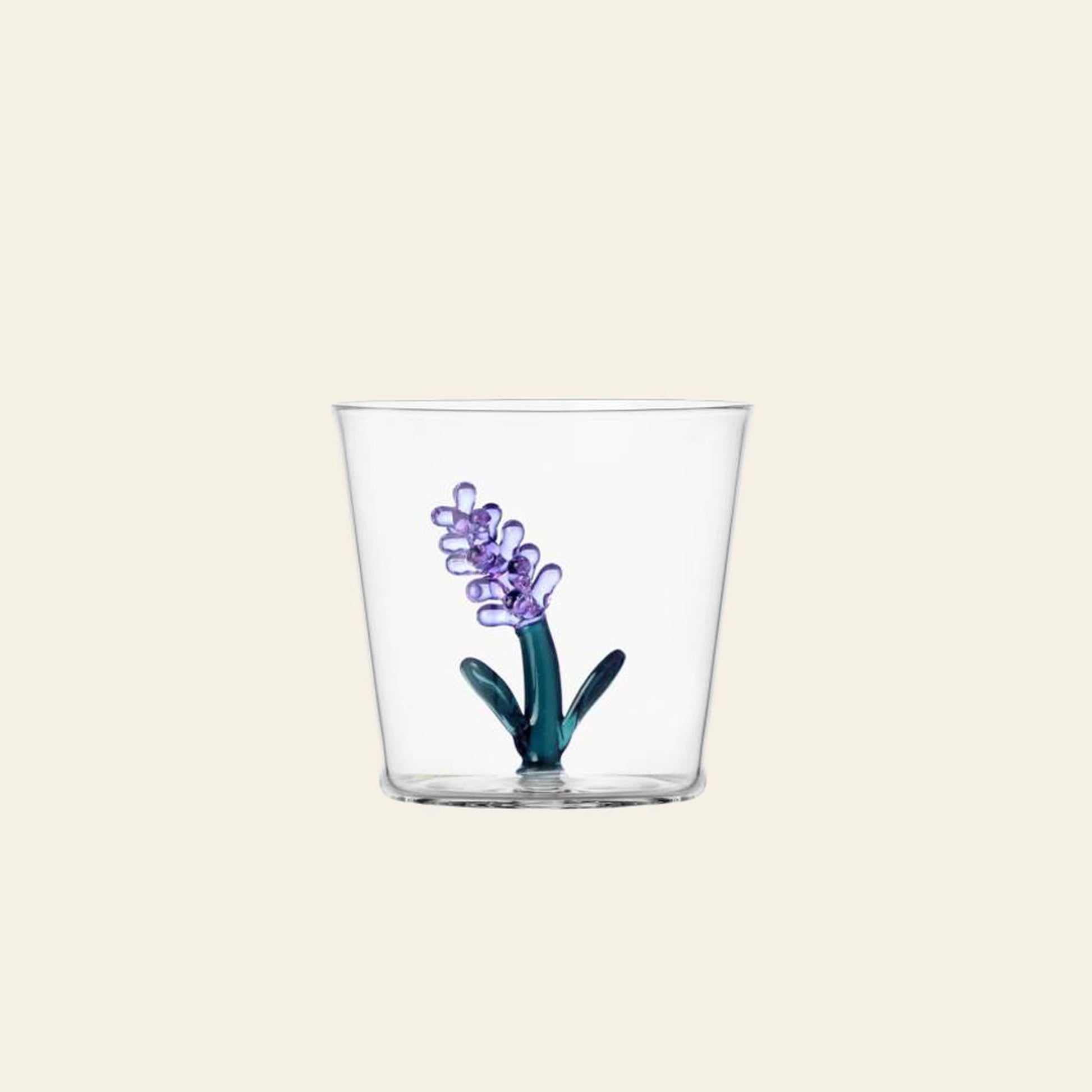 The Ichendorf Milano Botanica Tumbler - Lavender is a clear glass from Ichendorf Milano, adorned with a purple hyacinth flower, green stem, and leaves design on a plain light background.