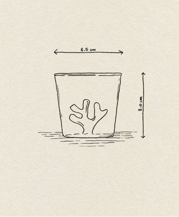 The Ichendorf Milano Coral Reef Tumbler by Ichendorf Milano features a simple line drawing of a glass with a coral-shaped object inside, resembling an underwater reef. The tumbler measures 8.5 cm wide and 8 cm tall, as shown beside and above the glass.