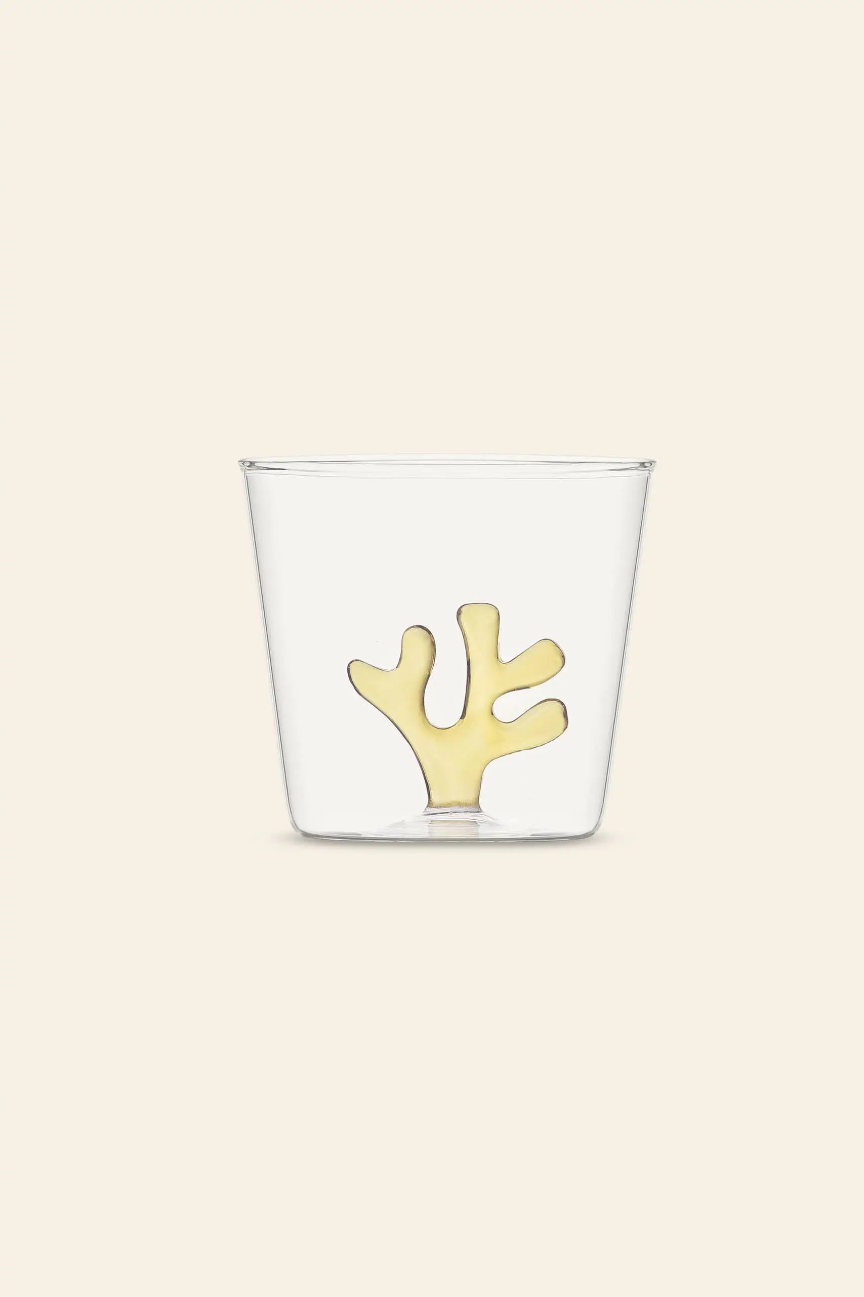 The Ichendorf Milano Coral Reef Tumbler by Ichendorf Milano features a clear glass with a yellow coral-inspired design, set on a light beige background. This elegant piece reflects Alessandra Baldereschi’s love for underwater ecosystems.