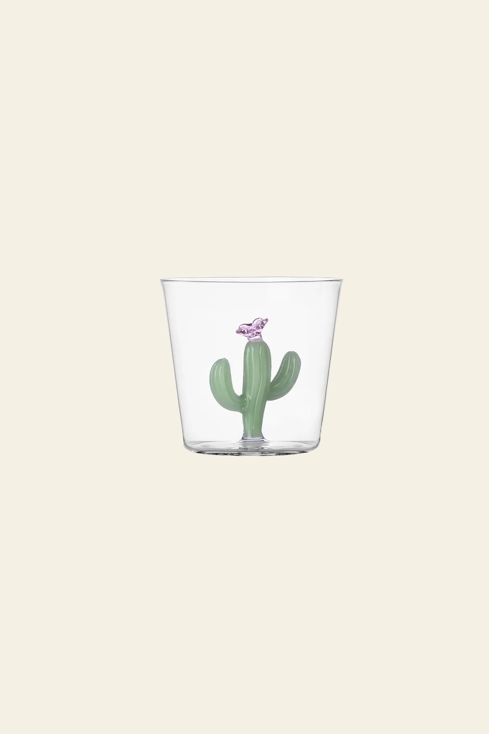 The Ichendorf Milano Desert Plants Tumbler is a clear glass cup from the Ichendorf Milano collection, featuring a small green cactus motif and a purple bird figurine inside, displayed against a plain beige background.