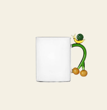 The Ichendorf Milano Fruits and Flower Mug features a playful abstract handle with yellow and green accents—an eye-catching clear glass design by Ichendorf Milano, perfect for any fruit and flower mug collection.