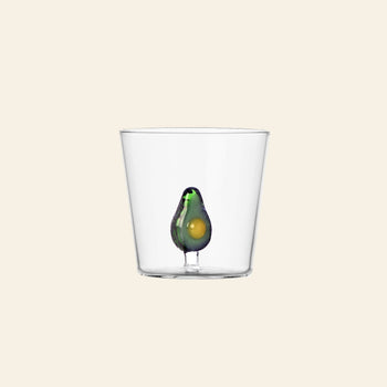 A clear Ichendorf Milano Fruits and Flowers Tumbler, featuring a small decorative avocado motif by Alessandra Baldereschi, displayed against a plain light beige background.