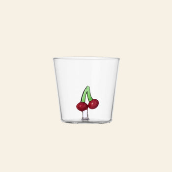 The Ichendorf Milano Fruits and Flowers Tumbler by Ichendorf Milano is a clear glass featuring a small, hand-painted design of two red cherries with green stems near the base, set against a light beige background.