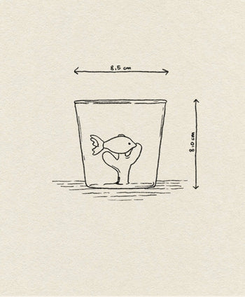 A simple sketch shows a fish in the Ichendorf Milano Marine Garden Tumbler, with hand-shaped water cupping the fish. The glass is 8.5 cm wide and 8.0 cm tall, set against a plain, lightly textured paper background.