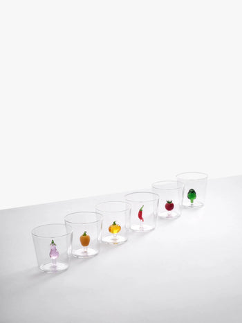 Six Ichendorf Milano Vegetables Tumblers are lined up, each showcasing a unique hand-blown glass figurine—onion, orange, pumpkin, chili pepper, eggplant, and green pepper—creating a charming display by Ichendorf Milano. White background.