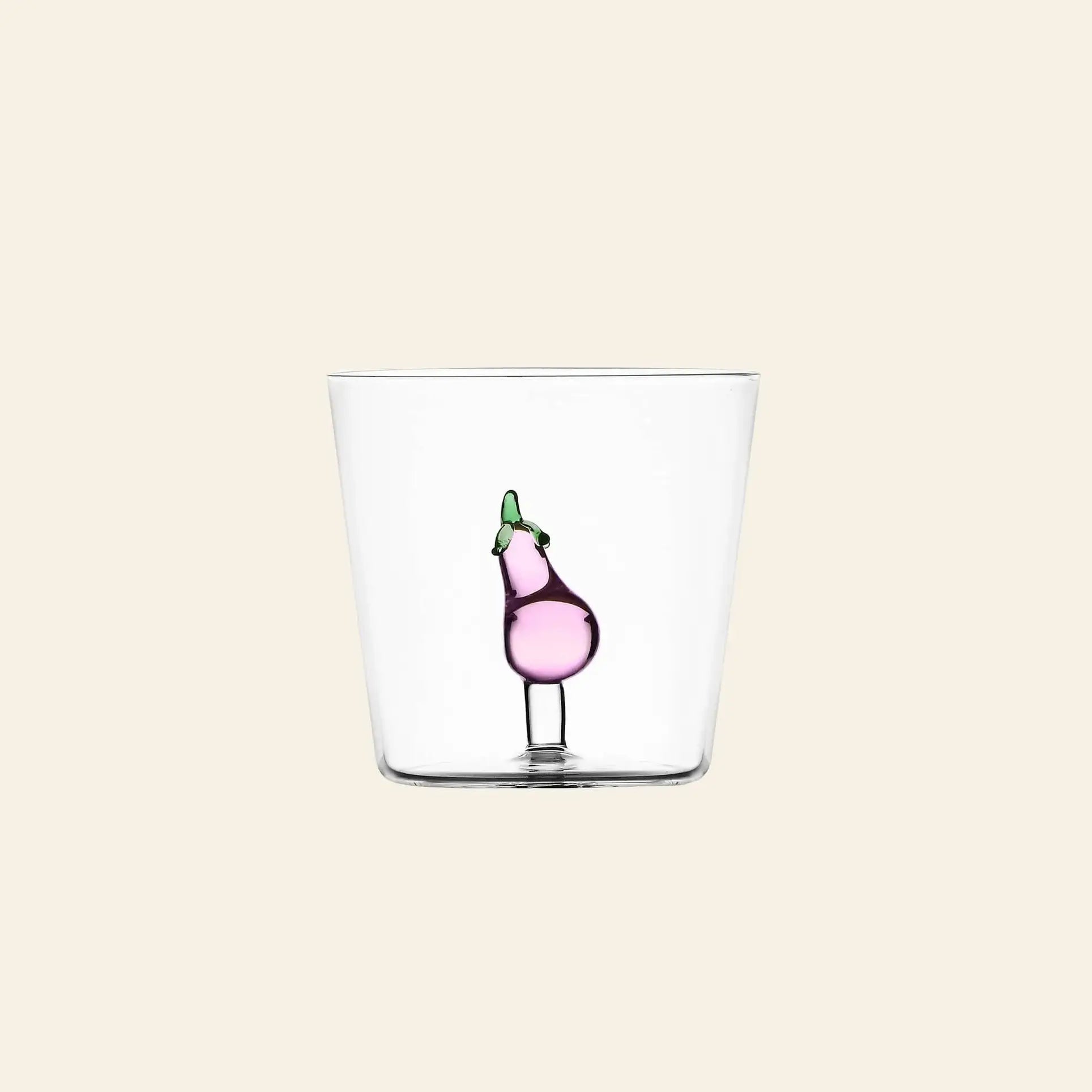 The Ichendorf Milano Vegetables Tumbler is a clear glass from Ichendorf Milano, decorated with a small handcrafted purple eggplant, perfect as a unique gift and shown against a plain beige background.