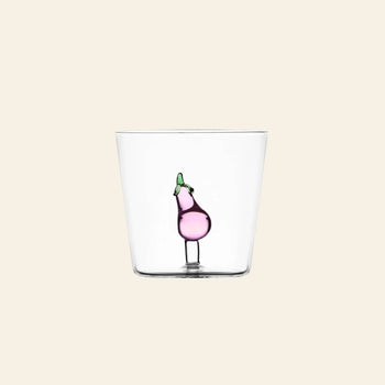 The Ichendorf Milano Vegetables Tumbler is a clear glass from Ichendorf Milano, decorated with a small handcrafted purple eggplant, perfect as a unique gift and shown against a plain beige background.
