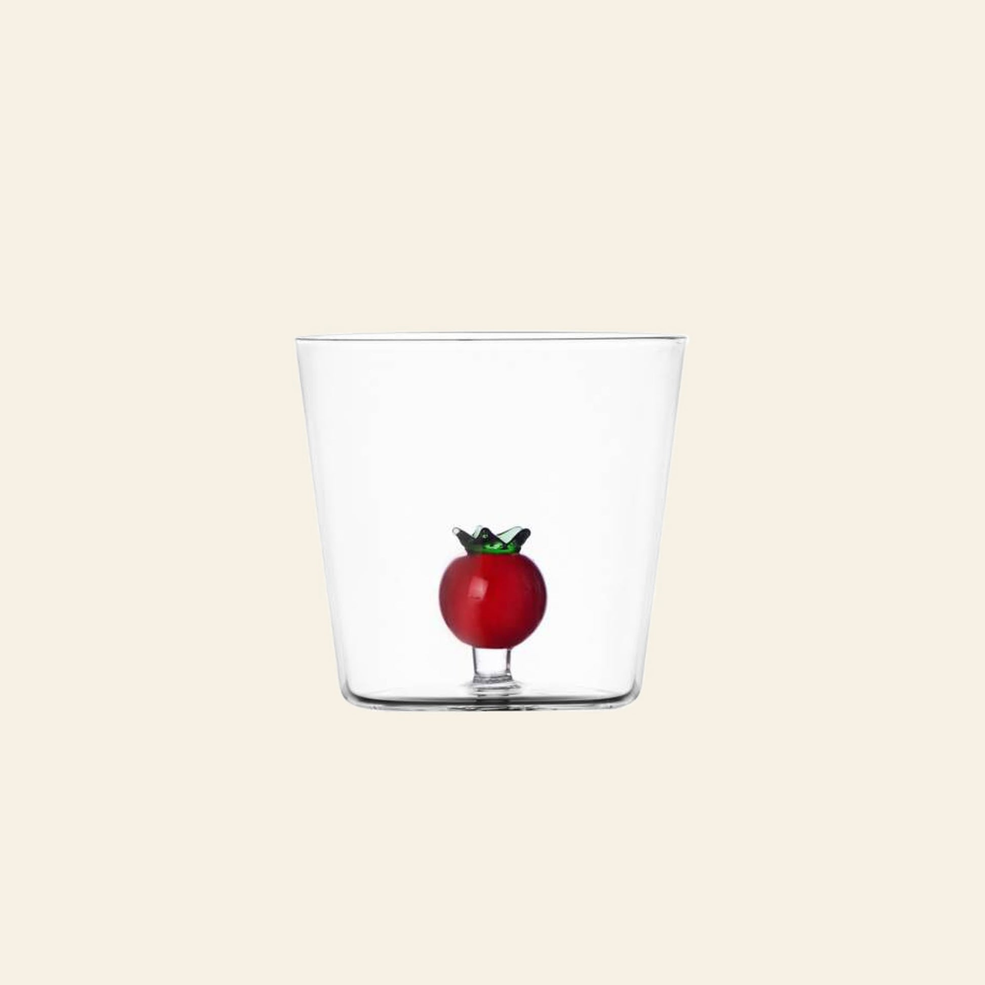 The Ichendorf Milano Vegetables Tumbler by Ichendorf Milano features hand-blown clear glass with a decorative red tomato and green stem inside—ideal as a unique gift or for your vegetables collection. Shown on a plain beige background.