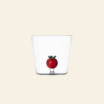 The Ichendorf Milano Vegetables Tumbler by Ichendorf Milano features hand-blown clear glass with a decorative red tomato and green stem inside—ideal as a unique gift or for your vegetables collection. Shown on a plain beige background.