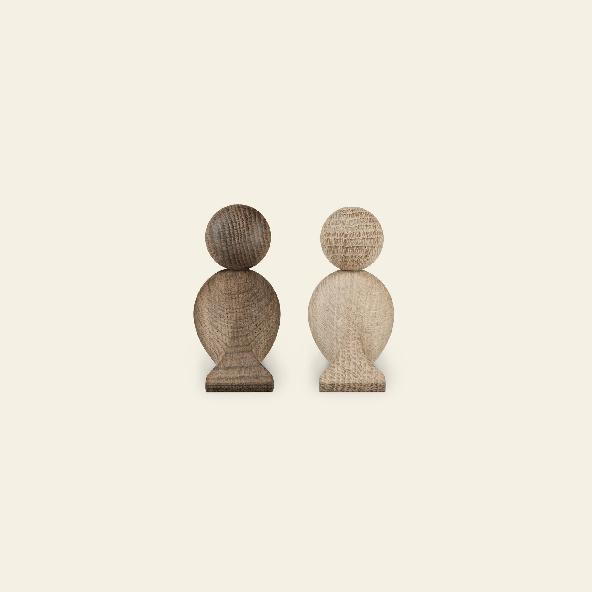 The Kay Bojesen Lovebirds Pair by Kay Bojesen features two wooden figurines, one dark and one light, standing side by side—showcasing charming Danish craftsmanship against a plain, light background.