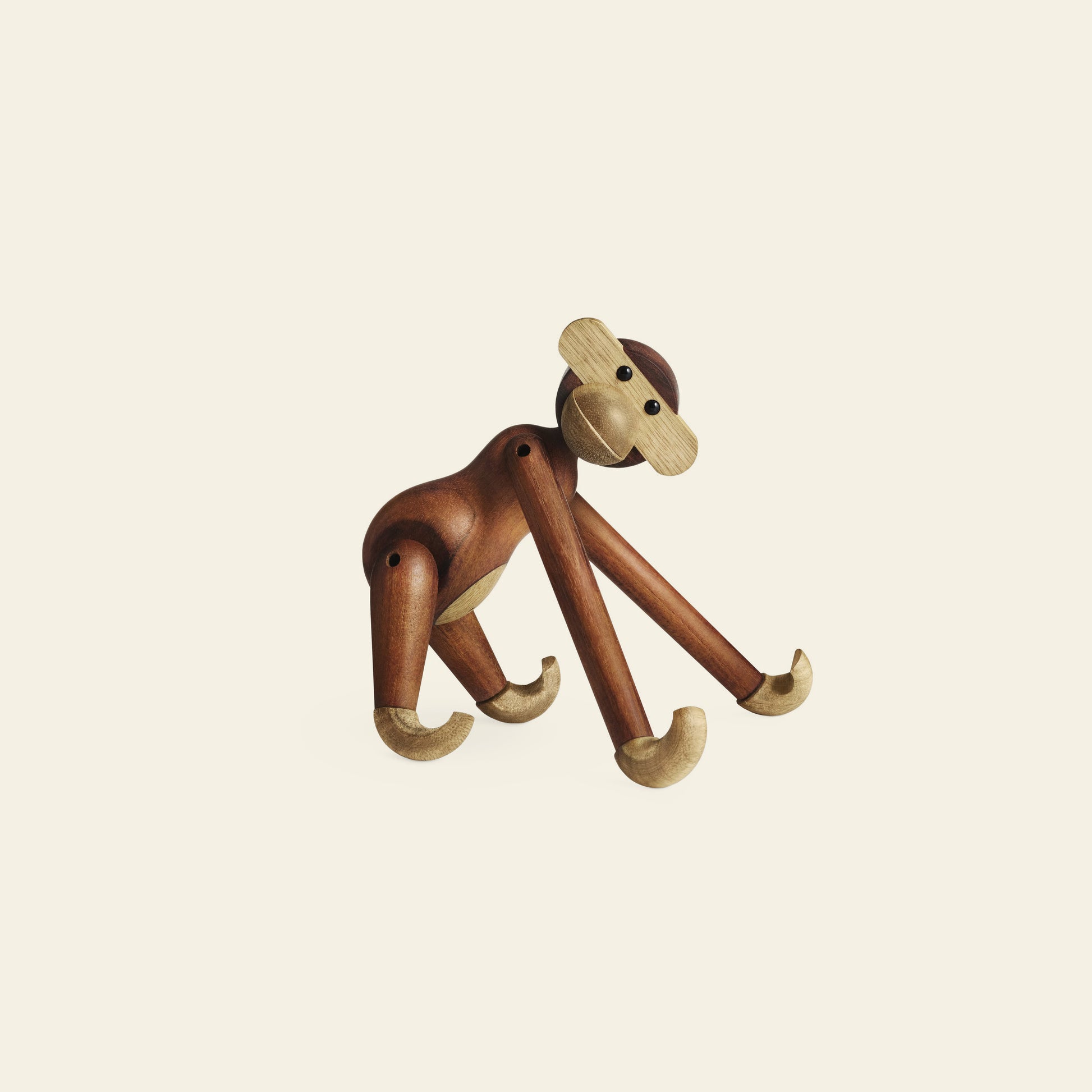 The Kay Bojesen Monkey Small by Kay Bojesen is a timeless wooden figurine with movable limbs in contrasting light and dark wood, shown standing on all fours against a plain, light background.