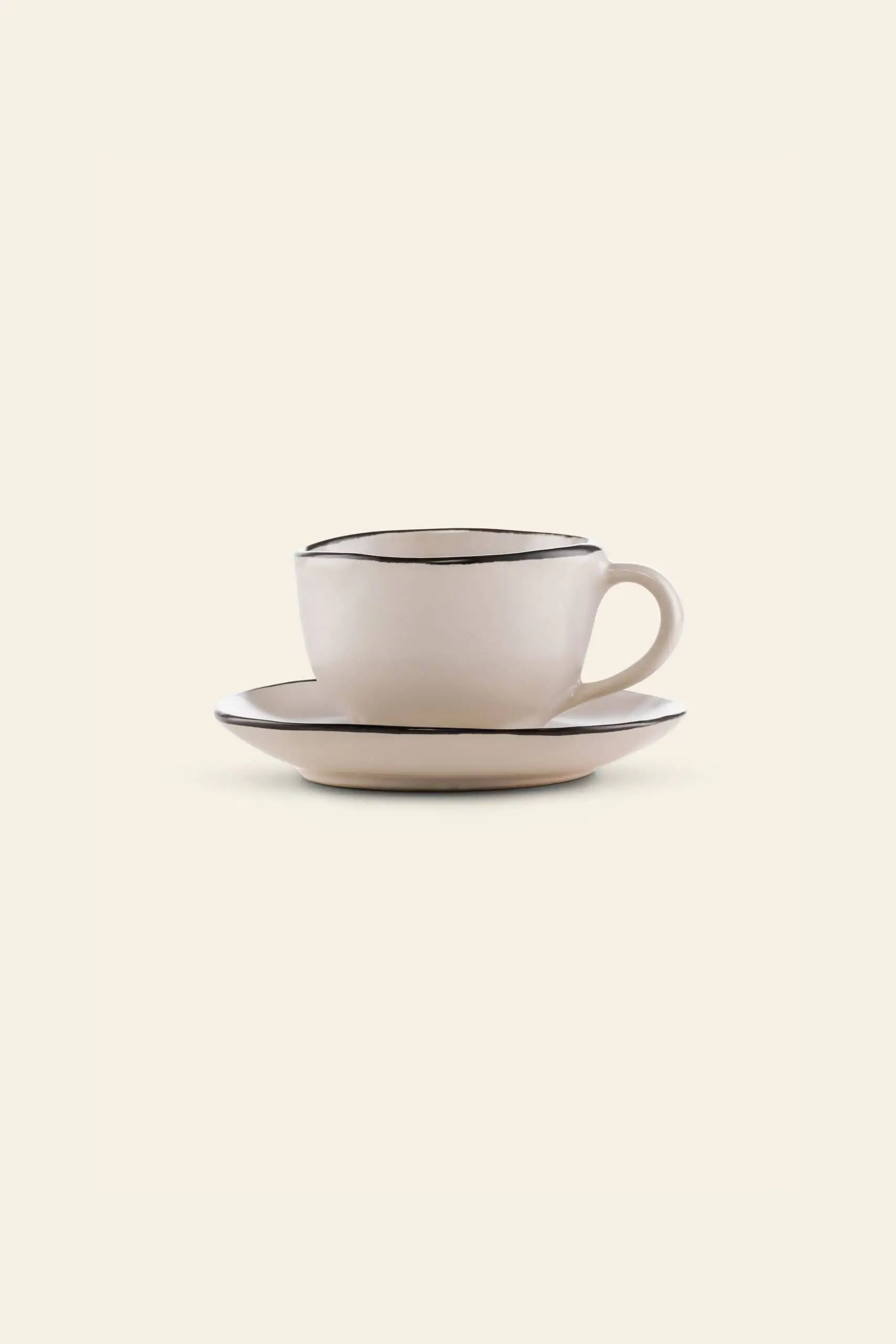 The Kra Sanctuary Andaman Free-Form Cup with handle and matching coaster features an off-white finish with thin, dark rims, bringing relaxed island elegance to your diningware. Shown on a plain, light background.