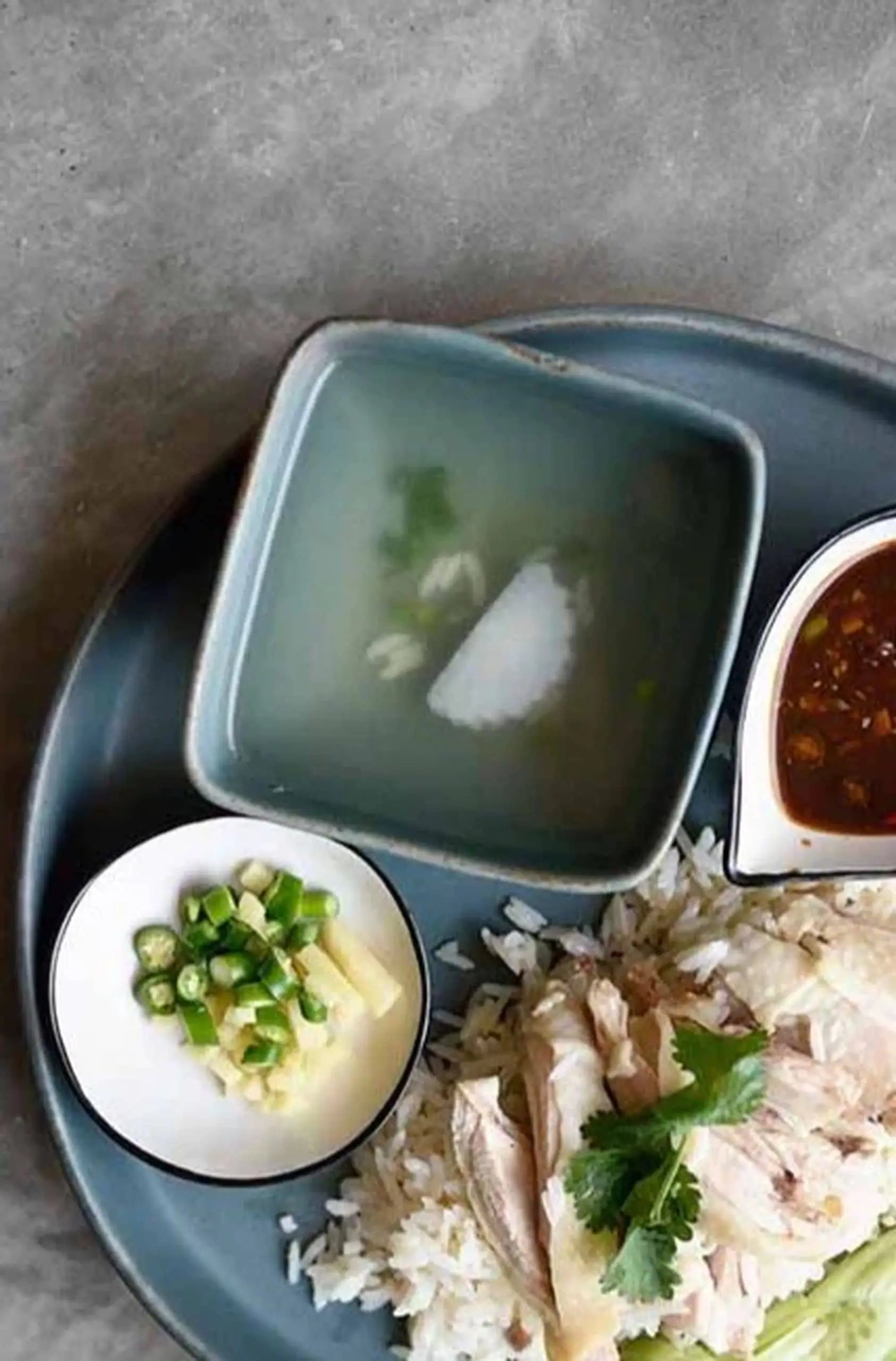 The Kra Sanctuary Karst Square Snack Bowl by Kra Sanctuary brings rustic charm to your table, perfect for serving rice with sliced chicken, cilantro, soup, dipping sauce, and sides of green chili and ginger.