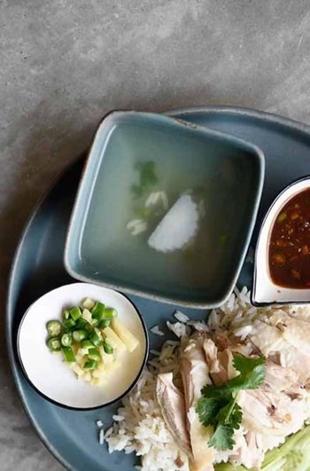 The Kra Sanctuary Karst Square Snack Bowl by Kra Sanctuary brings rustic charm to your table, perfect for serving rice with sliced chicken, cilantro, soup, dipping sauce, and sides of green chili and ginger.