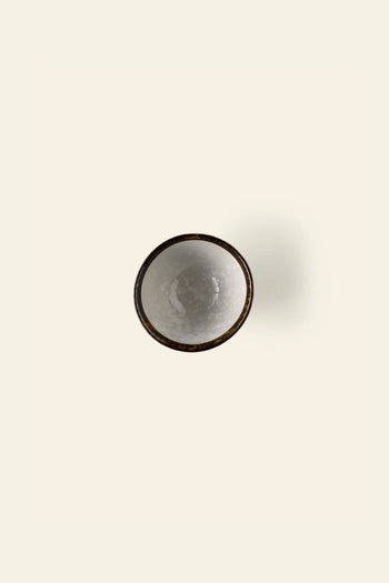 The Kra Sanctuary Satay Everyday Rice Bowl by Kra Sanctuary, a small round ceramic bowl filled with white liquid and viewed from above, is centered on a plain off-white background—bringing elegance to any dining experience.