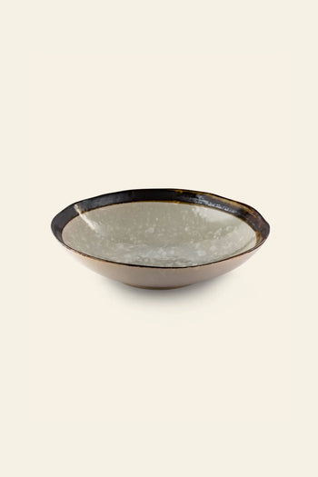 The Kra Sanctuary Satay Free-Form Pasta Bowl is a shallow, round ceramic bowl with a glossy, speckled light gray interior and dark brown rim and exterior, perfect for elevating your dining experience. Brand: Kra Sanctuary.