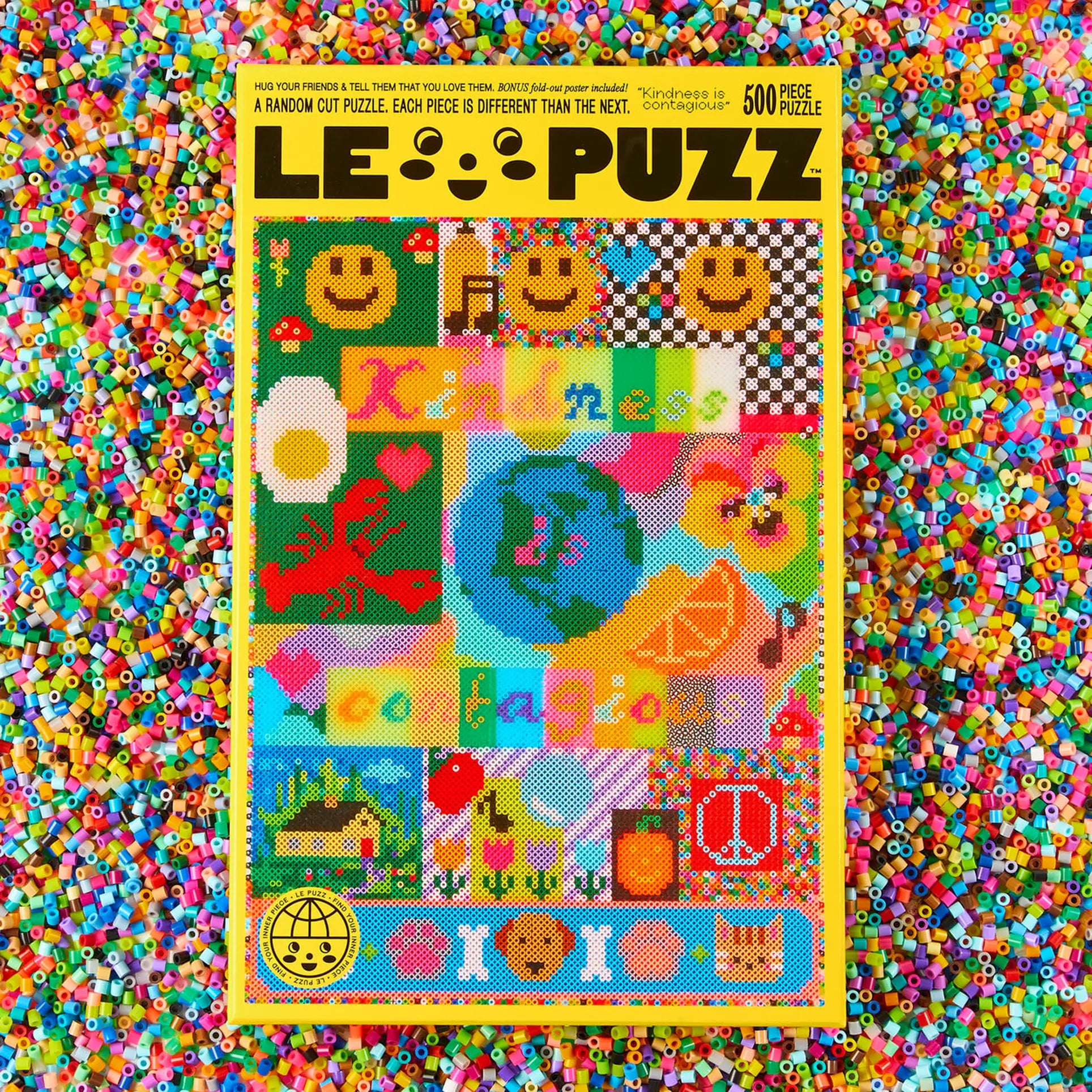 The Le Puzz Kindness is Contagious 500 Piece Puzzle by Le Puzz features a vibrant collage of pixel art and words like Kindness and Collaboration, with pearler beads scattered beneath.