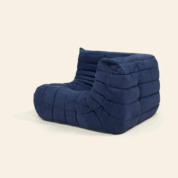 The Ligne Roset Togo Corner Seat by Ligne Roset is a modern, minimalist blue lounge chair with a low, armless design and plush, pleated fabric inspired by mid-century style, shown against a plain light background.