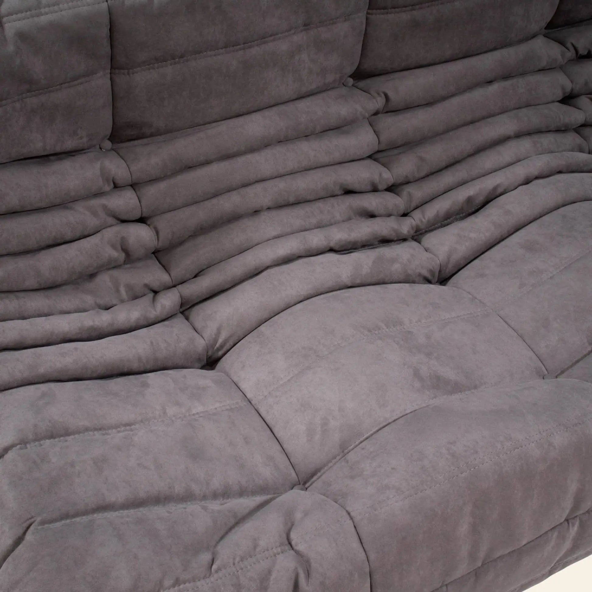 Close-up of the Ligne Roset Togo Corner Seat by Ligne Roset, featuring plush grey ruched upholstery and soft, comfortable cushions that highlight its modular design and detailed texture.