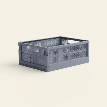 The Made Crate Midi by Made Crate is a lightweight, stackable gray rectangular storage crate made from recycled plastic with perforated sides and handles, shown on a light beige background.