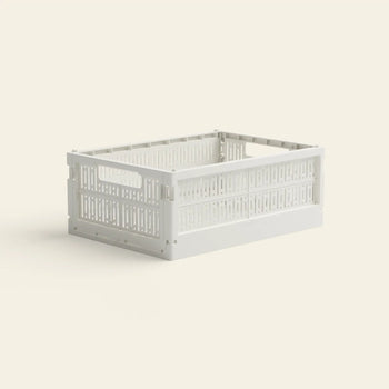 The Made Crate Midi by Made Crate is a white, rectangular, eco-friendly folding crate with open sides and handles at both ends, made from recycled plastic and displayed on a light beige background.