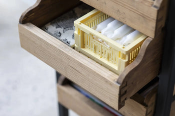 A wooden drawer is partially open, revealing a yellow Made Crate Mini by Made Crate filled with neatly arranged white tampons for organized, stackable storage.