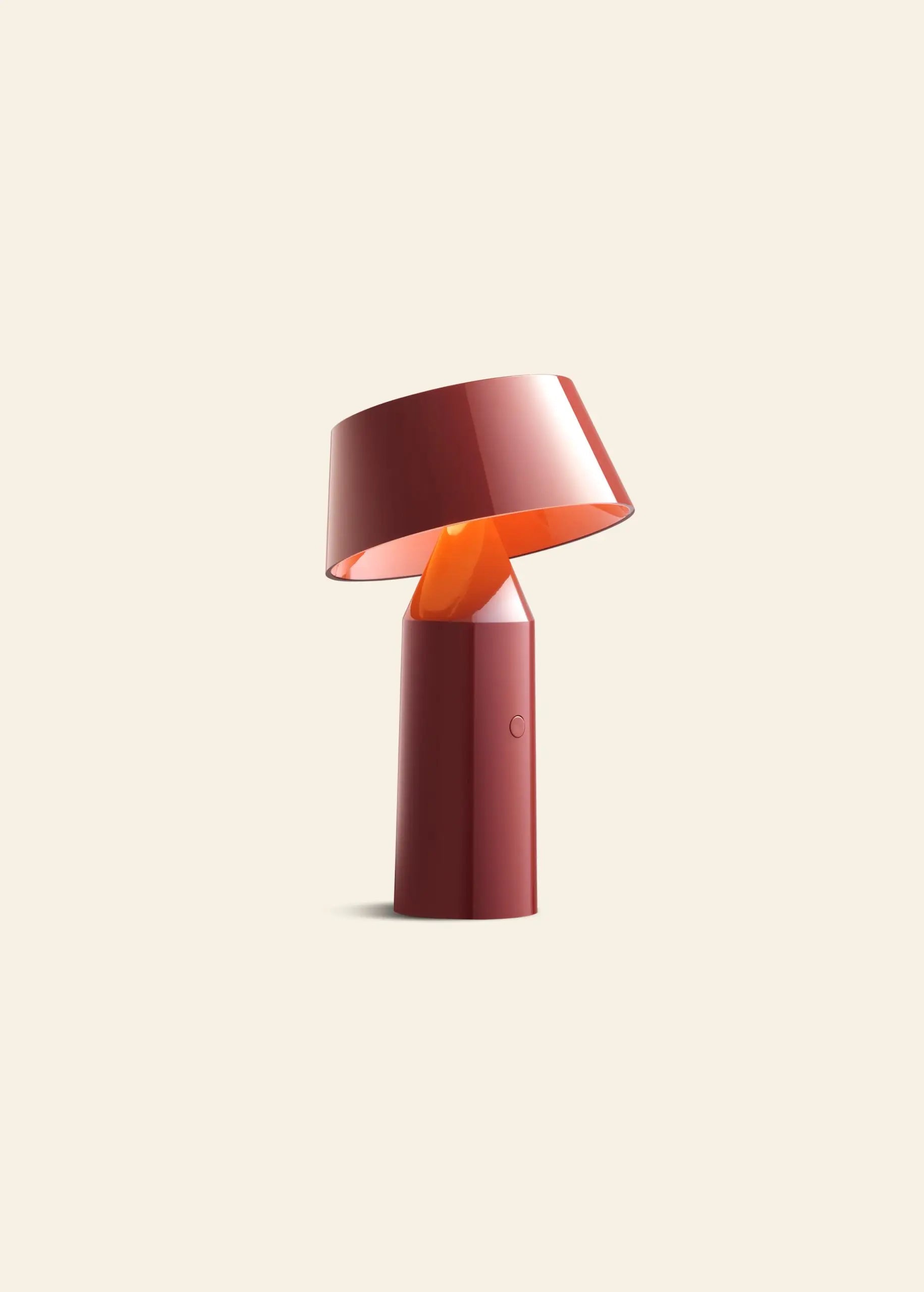 The Marset Bicoca Portable Table Lamp by Marset features a red cylindrical base and tilted glossy shade, set against a light beige background—an ideal modern lighting solution for contemporary spaces.