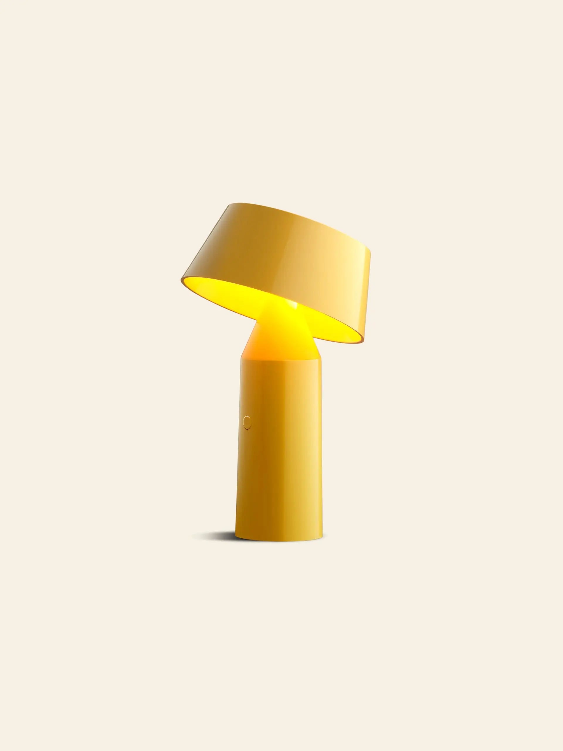 The Marset Bicoca Portable Table Lamp by Marset features a modern yellow design with a cylindrical base and tilted shade, casting warm light—ideal as a stylish table lamp for any space.
