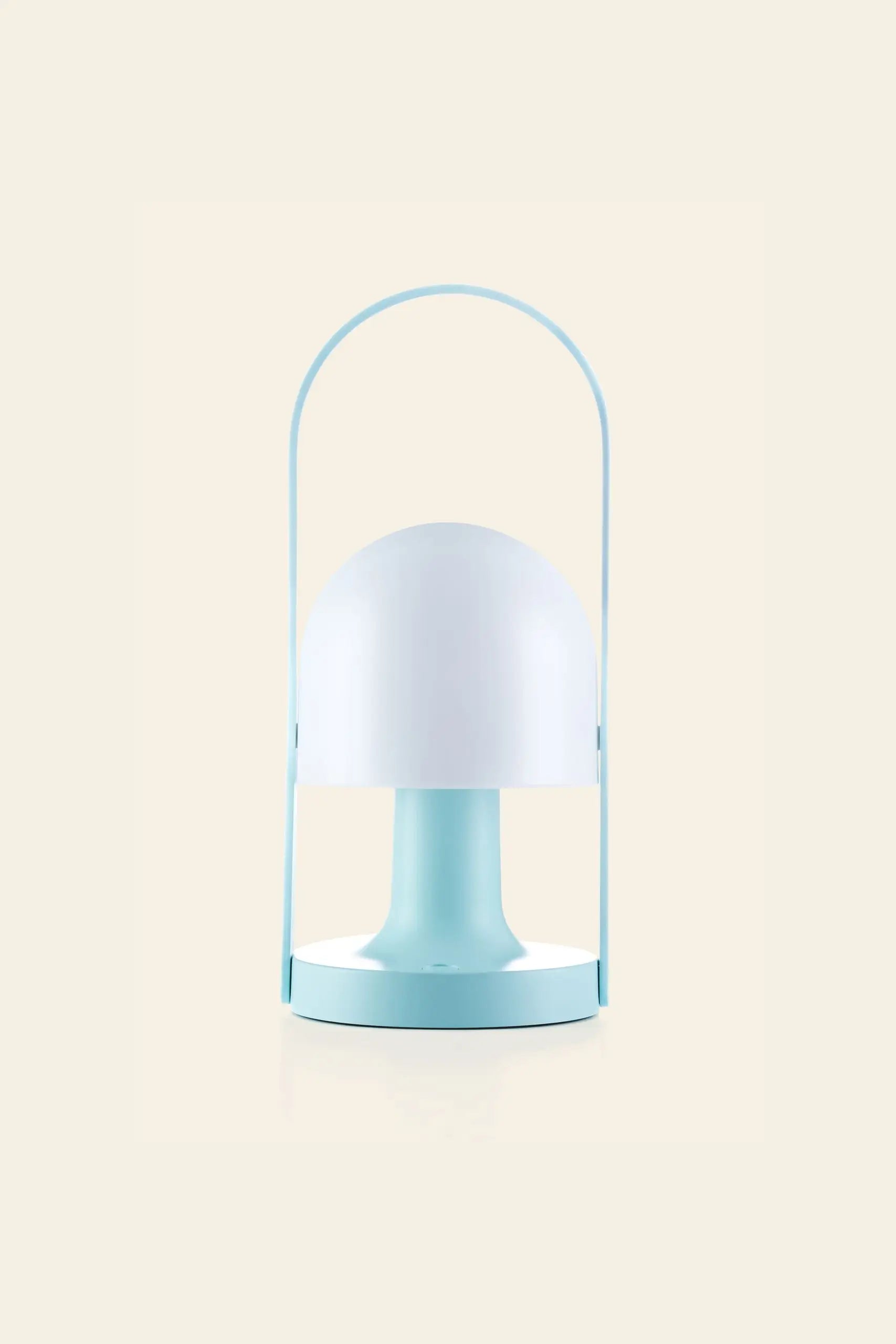 The Marset FollowMe Portable Table Lamp by Marset features a rounded white shade, light blue base, and matching blue handle. Rechargeable, modern, and minimalist, it’s a stylish lighting solution for any space. Displayed against a beige background.