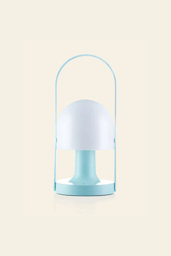 The Marset FollowMe Portable Table Lamp by Marset features a rounded white shade, light blue base, and matching blue handle. Rechargeable, modern, and minimalist, it’s a stylish lighting solution for any space. Displayed against a beige background.