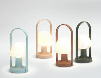 Four Marset FollowMe Portable Table Lamps by Marset in pastel blue, beige, brown, and dark green each feature a rounded dome-shaped white shade and an arched oak handle, displayed on a light background.