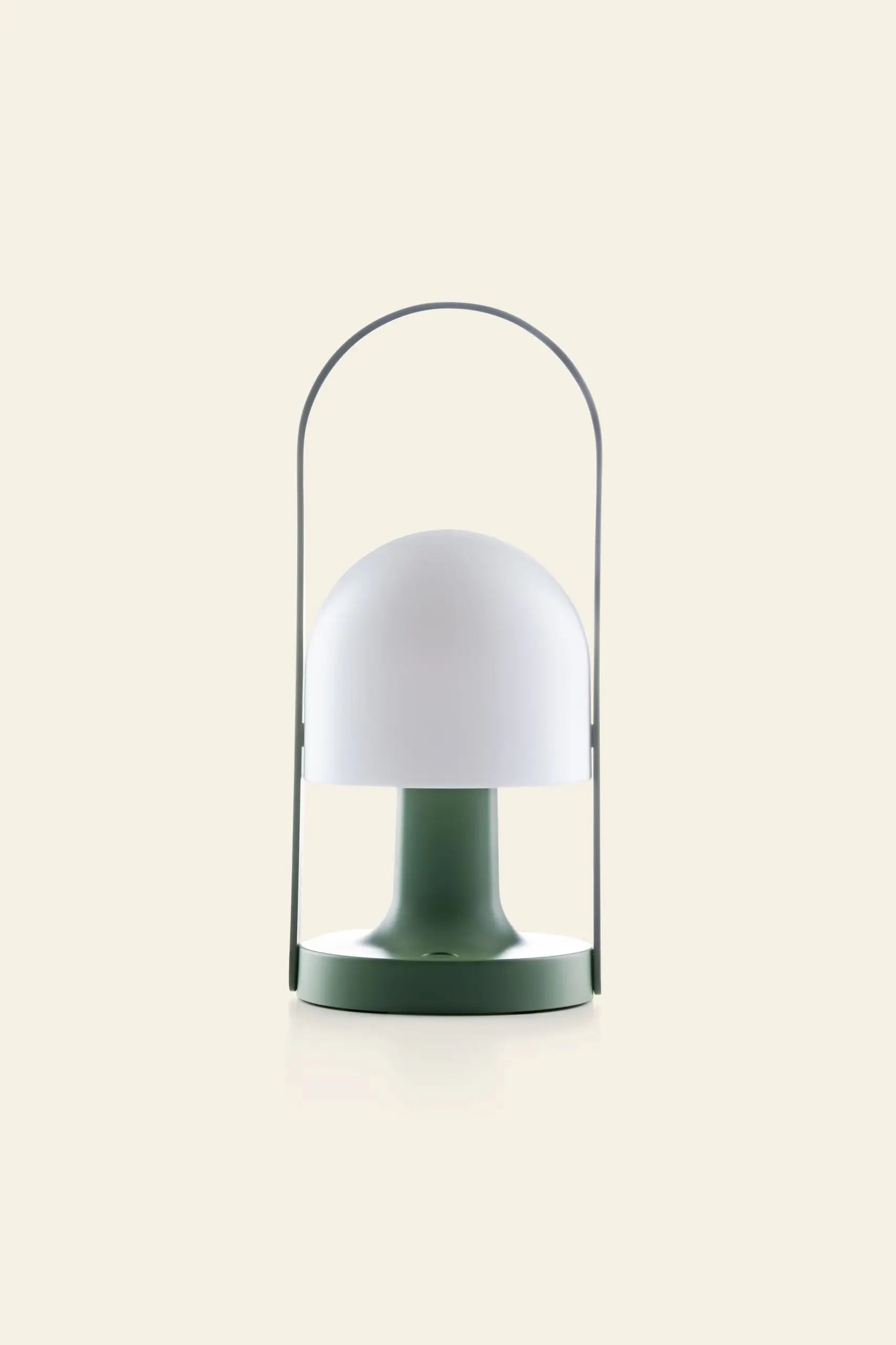 The Marset FollowMe Portable Table Lamp by Marset features a green base, dome-shaped white shade, and a sleek metal handle arching above, shown against a plain beige background.