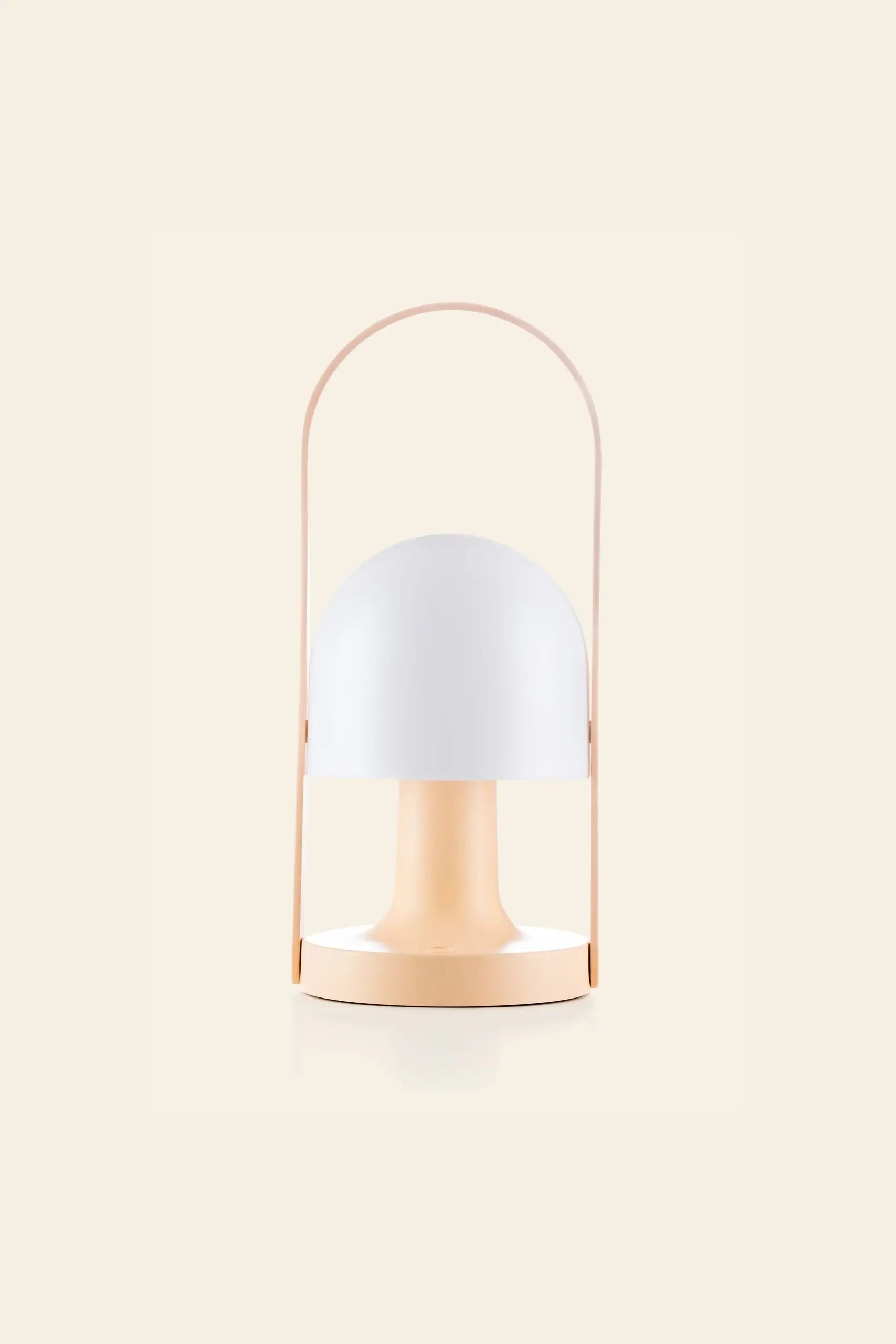 The Marset FollowMe Portable Table Lamp by Marset features a modern, minimalist design with a round white dome shade, light peach base, and matching arched handle, set against a plain cream background.