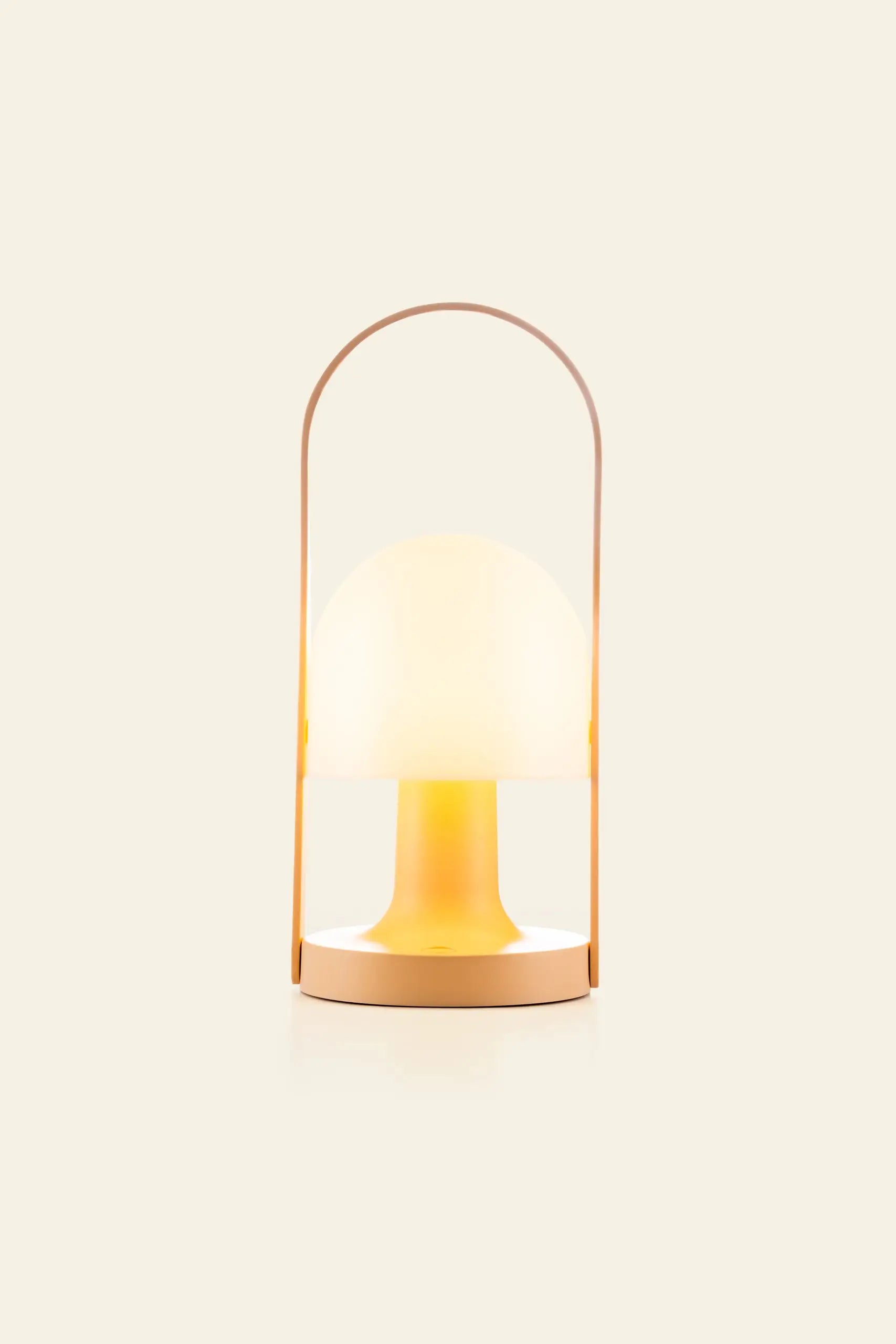 The Marset FollowMe Portable Table Lamp by Marset features a dome-shaped frosted glass shade, warm yellow glow, tan circular base, and matching oak handle, shown against an off-white background.