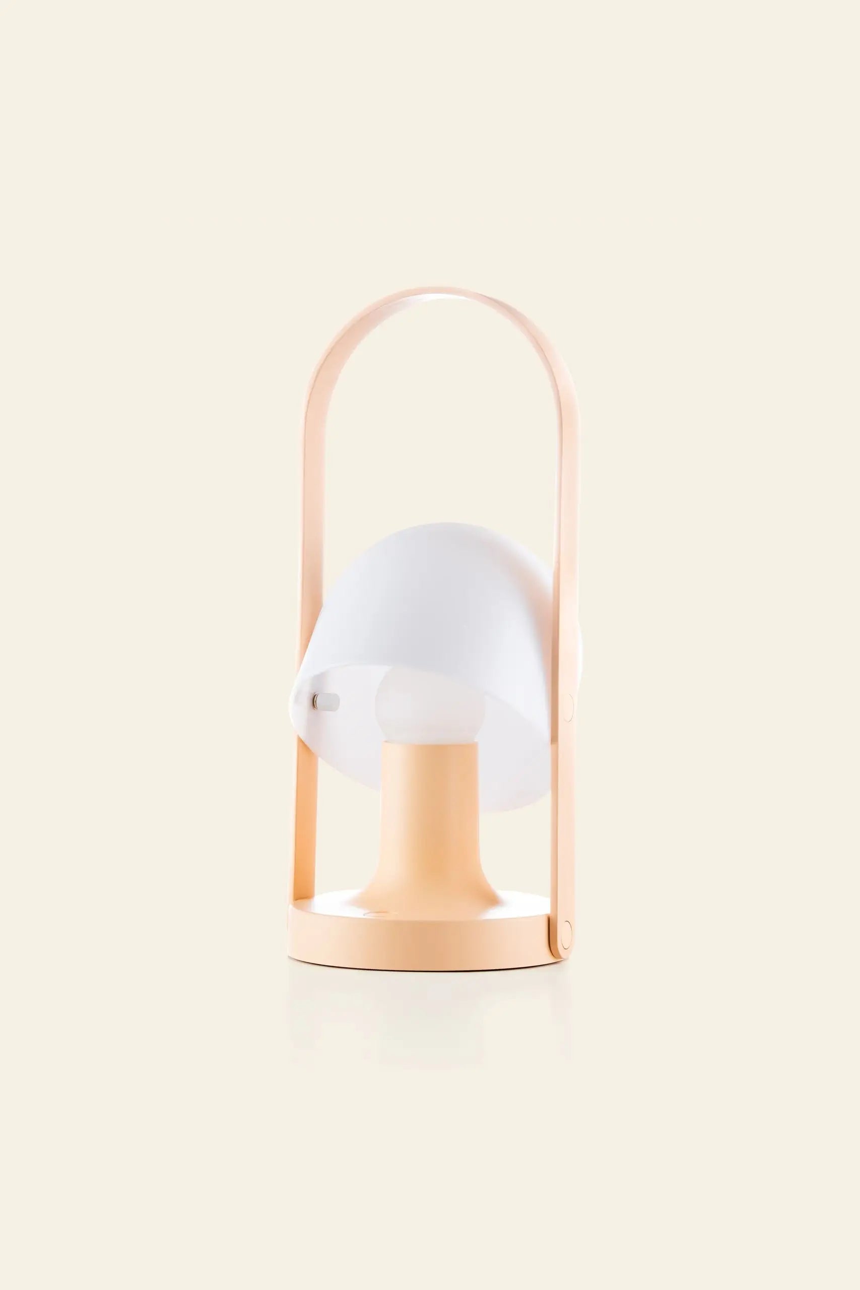 The Marset FollowMe Portable Table Lamp by Marset features a modern, minimalist design with a peach base, white mushroom-shaped shade, and arched oak handle, displayed against a plain light background.