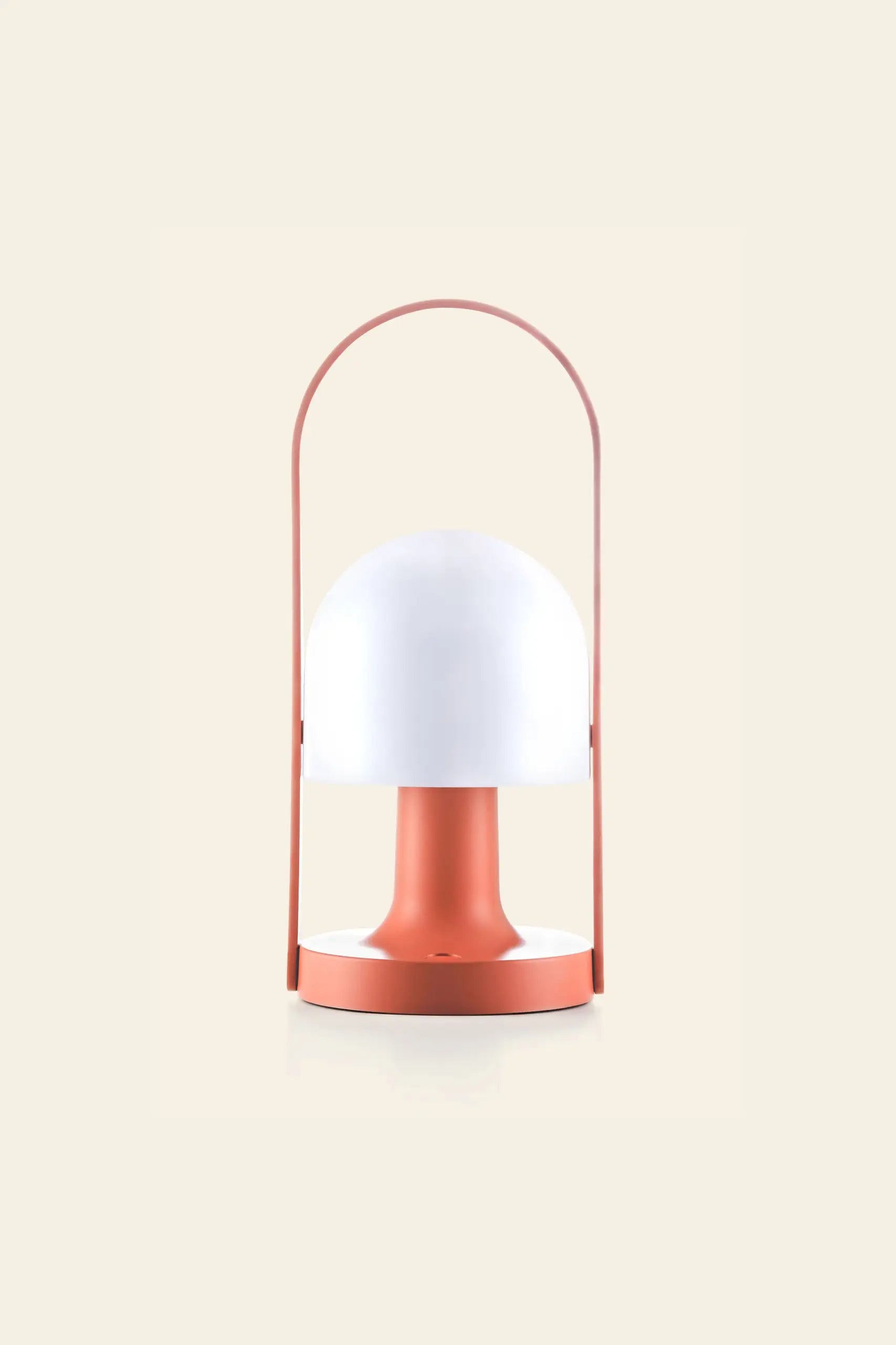 The Marset FollowMe Portable Table Lamp by Marset features a dome-shaped white top, coral base, and matching arched handle, shown against a plain beige background.