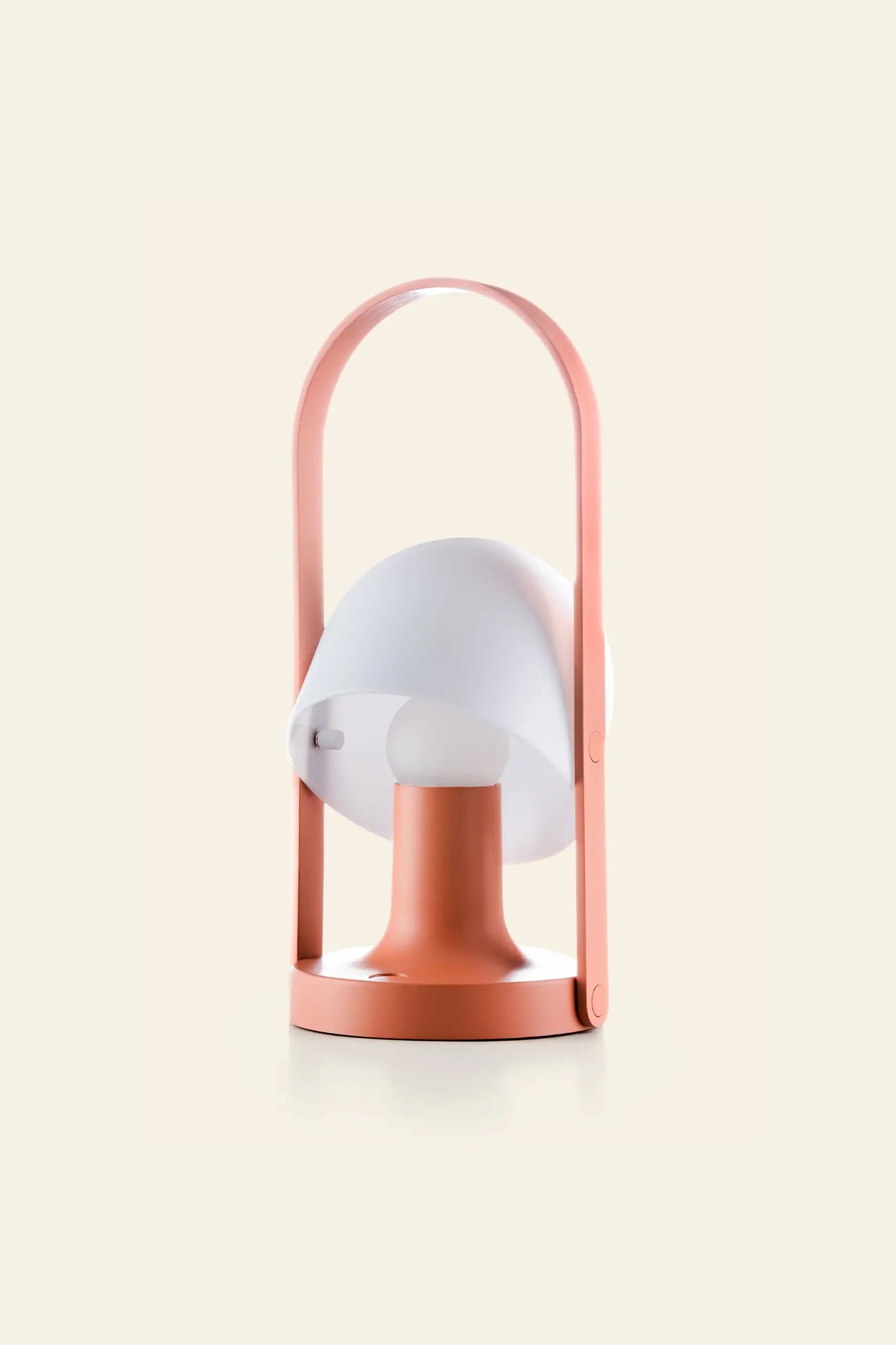 The Marset FollowMe Portable Table Lamp by Marset features a pink base and handle, a white dome-shaped shade, and is rechargeable. Stylish and portable, it’s perfect for any setting. Displayed against a light beige background.