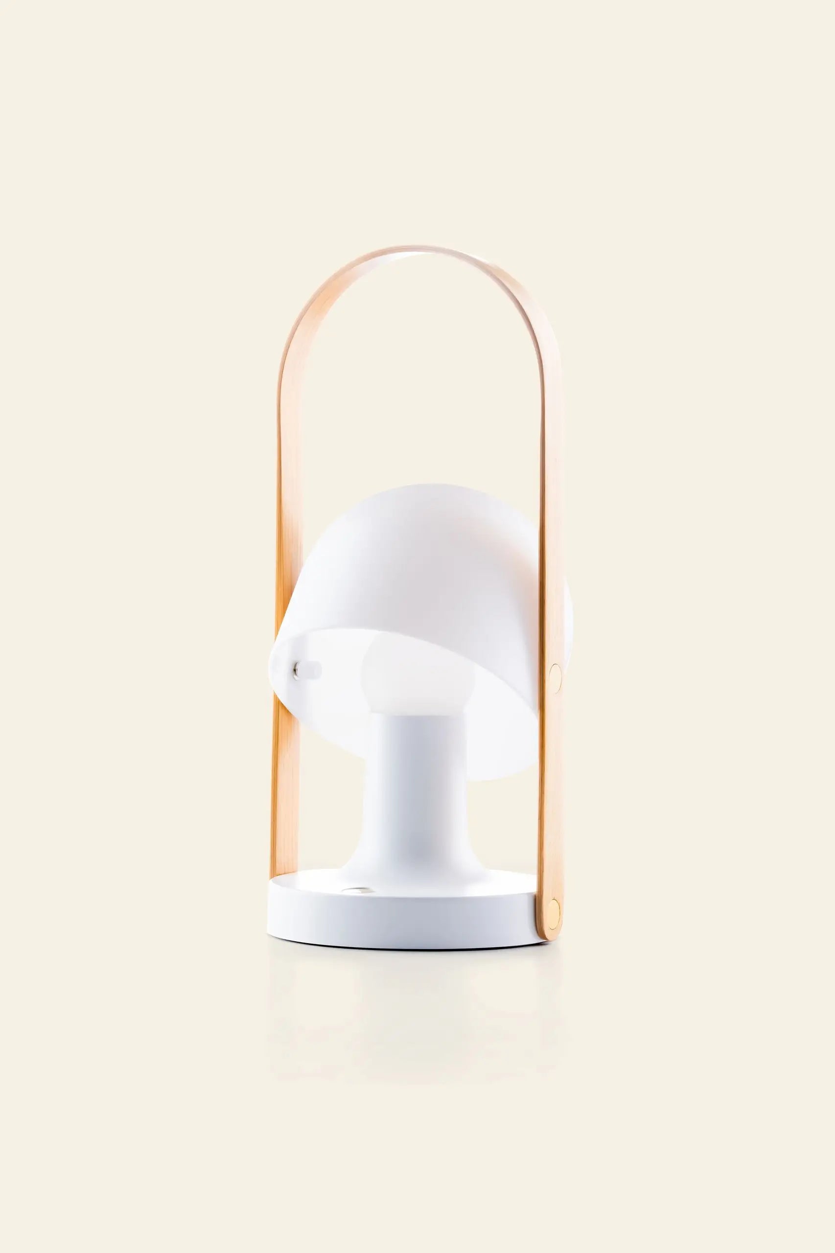 The Marset FollowMe Portable Table Lamp by Marset features a modern white rounded shade and an oak handle arching above, shown on a plain beige background.