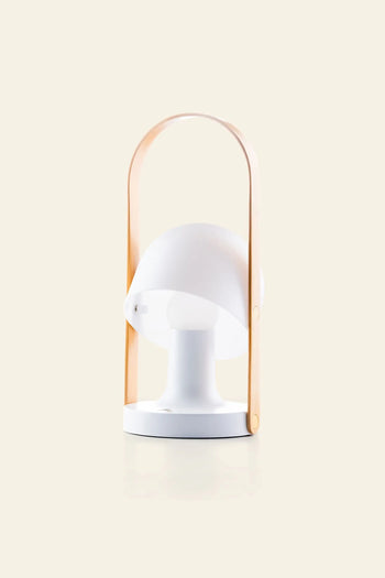The Marset FollowMe Portable Table Lamp by Marset features a modern white rounded shade and an oak handle arching above, shown on a plain beige background.