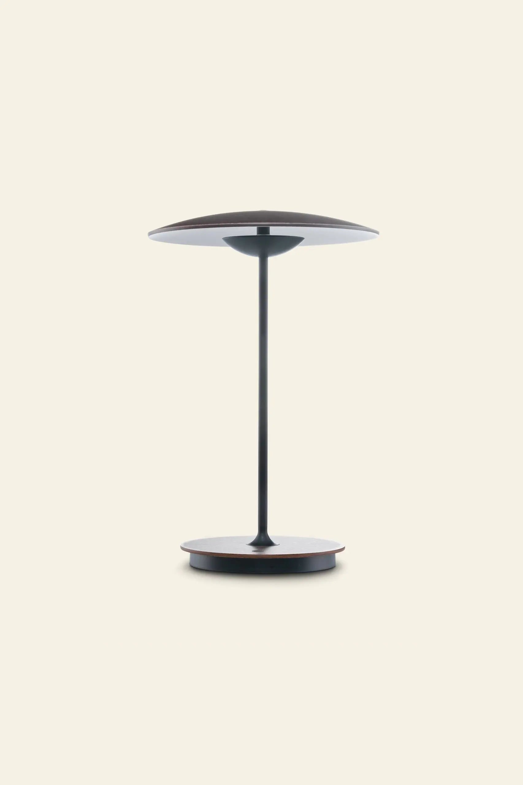 The Marset Ginger 20 M Table Lamp by Marset features a minimalist round design with a slim black metal base and double wooden shades, ideal for creating a cosy modern atmosphere against a plain beige backdrop.