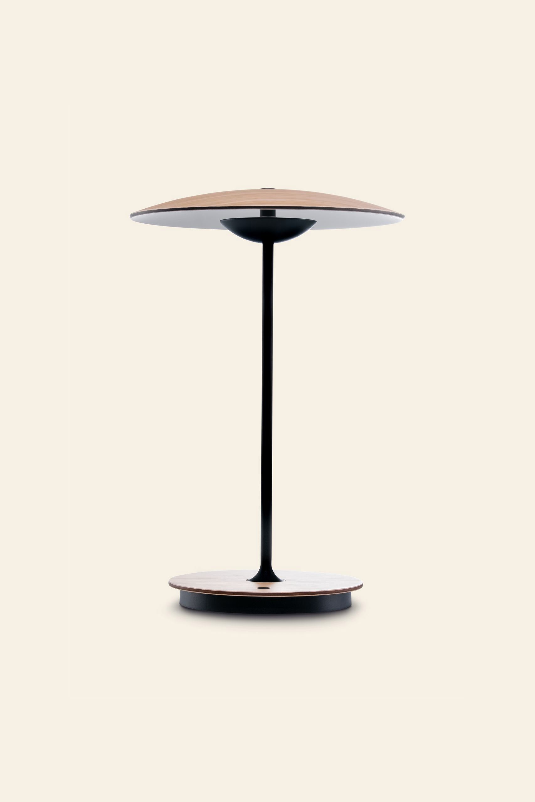 The Marset Ginger 20 M Table Lamp by Marset features a minimalist design with a round, light wood base and matching shade, linked by a sleek black stem—ideal for creating a cosy atmosphere in contemporary homes. Set on a plain beige background.