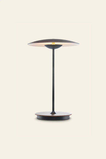 The Marset Ginger 20 M Table Lamp by Marset features a slim stem, circular base, and wide black and brown shade—ideal for bringing a cosy touch to modern decor against light backgrounds.