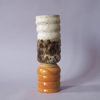 Three Mirjam Faber Ceramics Cappuccino Cup Bubble Edition cups are stacked vertically against a light purple background, highlighting the craftsmanship of Mirjam Faber Ceramics.
