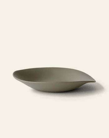 The NR Ceramics HIN Dessert Plate features a matte olive-green finish and organic, asymmetrical design—an elegant statement piece from NR Ceramics, shown here on a simple light background.